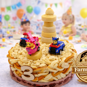 Detská kruhová syrová torta Labková patrola, ručne vypletaná torta zo syra s detskou oslavou v pozadí – Farma Tuška